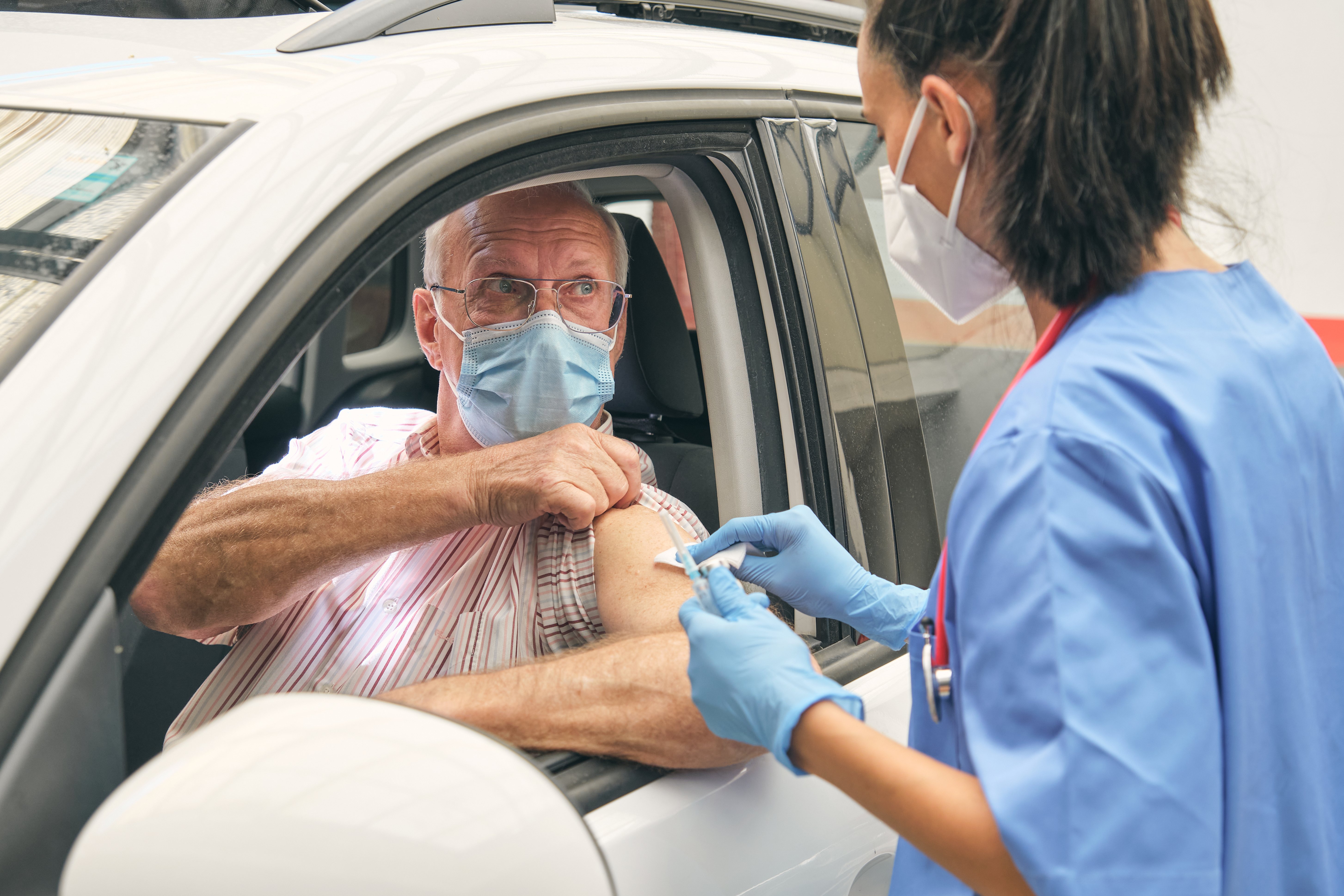 senior-man-receiving-vaccine-in-car-from-healthcar-2026-03-25-07-43-51-utc